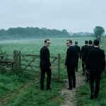 Illustration of men in dark suits walking off a path through a gate into an open field